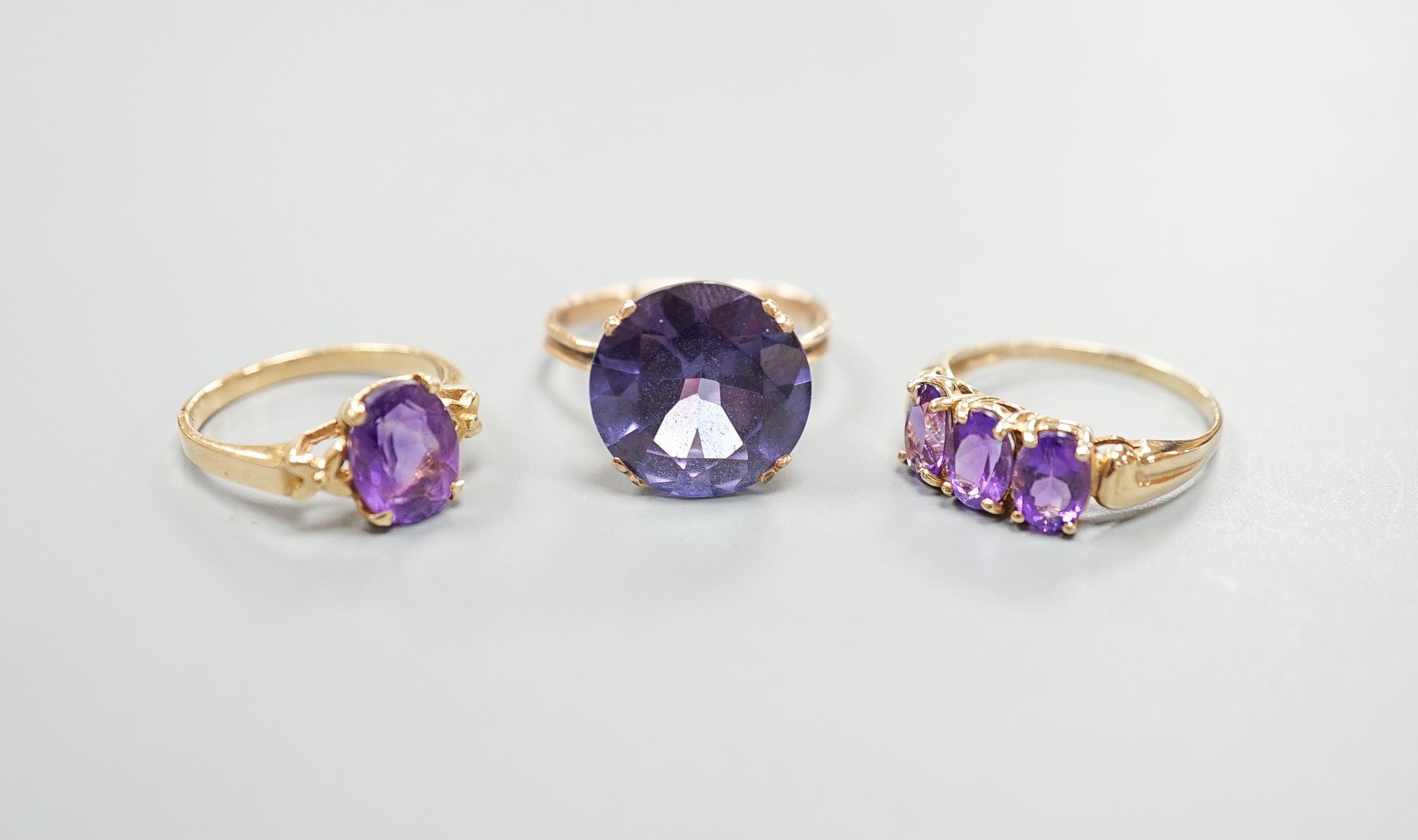 Two modern 14k yellow metal and gem set rings, including amethyst, size N, gross weight 7.4 grams and a similar 10k and three stone amethyst ring, size Q/R, gross 2.3 grams.